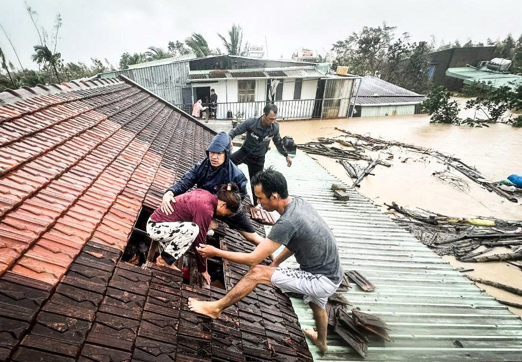 Nước lũ dâng lên sắp ngập mái nhà, người dân hỗ trợ dỡ mái ngói đưa người bên trong ra ngoài - Ảnh: Người dân cung cấp