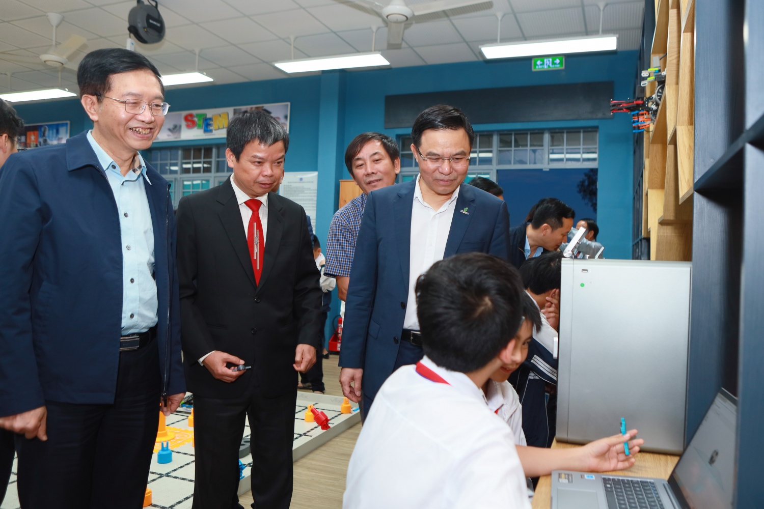 Các đại biểu thăm hỏi, trao đổi với các em học sinh về việc học tập với các thiết bị tại phòng STEM.